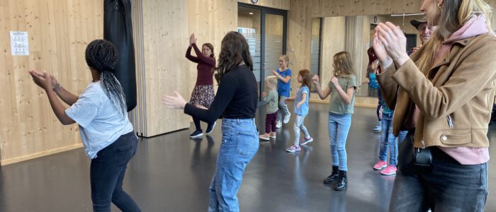 Gruppe von Besucher*innen, die eine Tanz im Fitnessraum einstudieren
