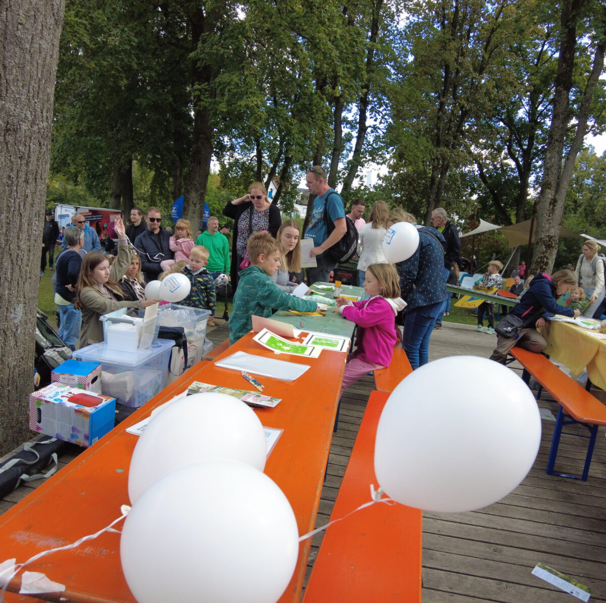 Bastelaktion beim KFF'23 Kinder sitzen am Tisch und Basteln, viele Besucher im Hintergrund auf dem Gelädne rund um das Jugendhaus