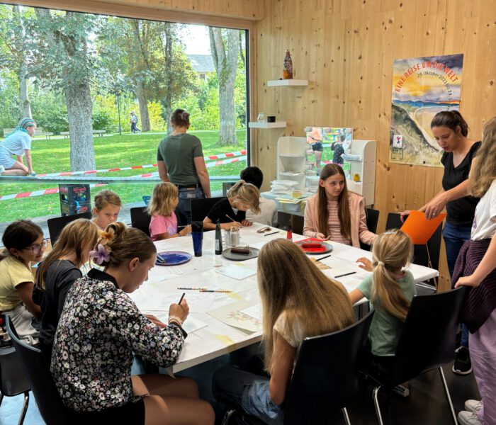 Kinder sitzen am Tisch und bemalen Postkarten beim Kinder- und Familienfest 2024