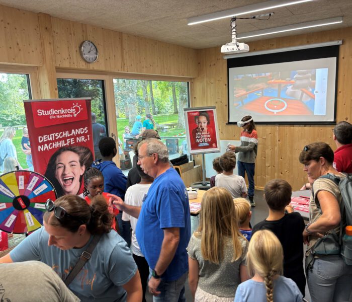 Bild des Gewinnspiels beim Kinder- und Familienfest 2024, im Hintergrund spielt ein Kind mit einer VR-Brille auf dem Kopf ein Lernspiel