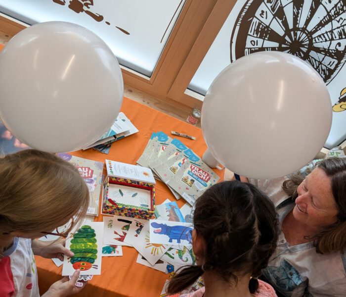 Bild eines Bastelangebotes beim Kinder- und Familienfest 2024 Kinder halten Luftballons in den Händen und nehmen Ausmalbilder entgegen